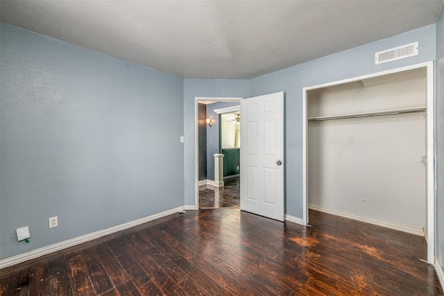 unfurnished bedroom with a closet and dark hardwood / wood-style floors