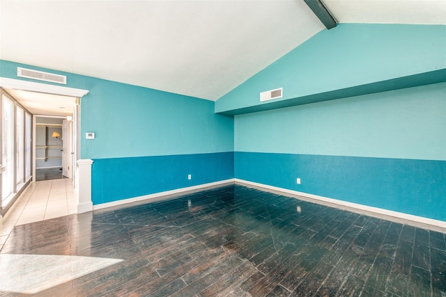 spare room with wood-type flooring and vaulted ceiling with beams