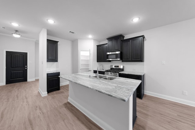 kitchen featuring stainless steel appliances, sink, a center island with sink, and light hardwood / wood-style flooring