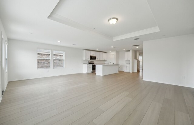 kitchen with an island with sink, range with electric stovetop, sink, and tasteful backsplash