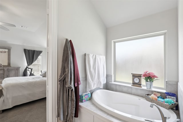 bathroom featuring tiled tub, ceiling fan, vaulted ceiling, and a healthy amount of sunlight