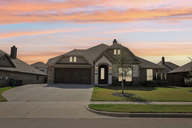 french country inspired facade featuring a garage and a lawn