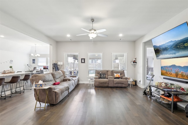 living room featuring ceiling fan with notable chandelier and dark wood-type flooring