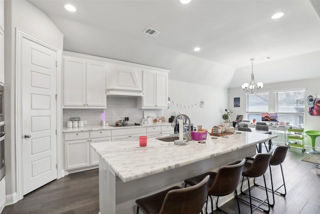 kitchen featuring pendant lighting, vaulted ceiling, dark wood-type flooring, and sink