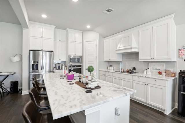 kitchen with stainless steel appliances, an island with sink, and dark hardwood / wood-style floors