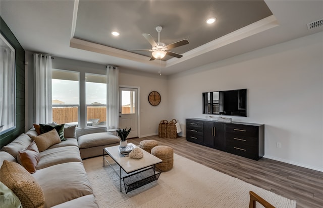 living room with ceiling fan, a tray ceiling, and light hardwood / wood-style floors