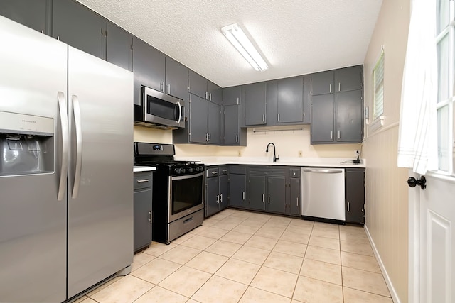 kitchen featuring light tile patterned floors, sink, stainless steel appliances, and a textured ceiling