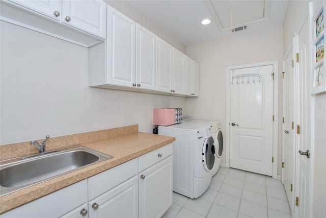 laundry area with light tile patterned flooring, separate washer and dryer, sink, and cabinets