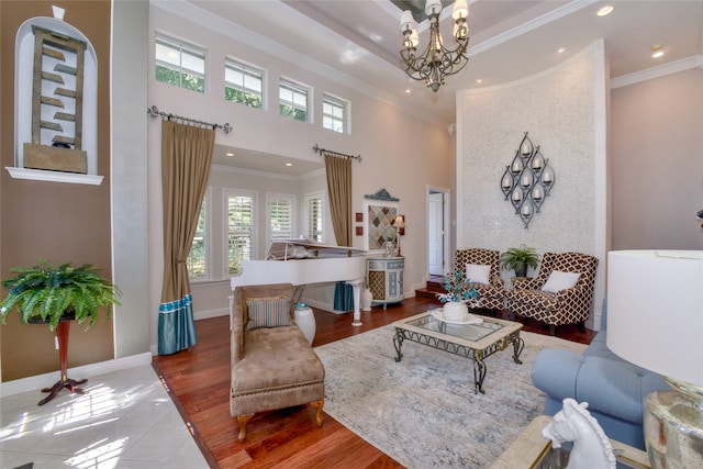 living room with a towering ceiling, wood-type flooring, ornamental molding, and a notable chandelier