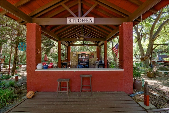 wooden deck featuring a gazebo, a grill, exterior bar, and ceiling fan