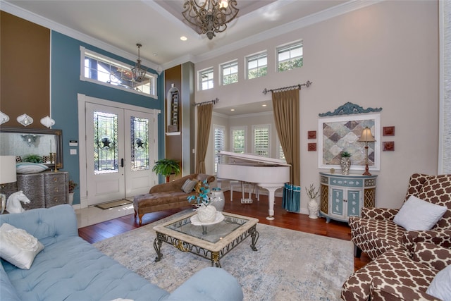 living room with french doors, hardwood / wood-style flooring, a high ceiling, crown molding, and an inviting chandelier