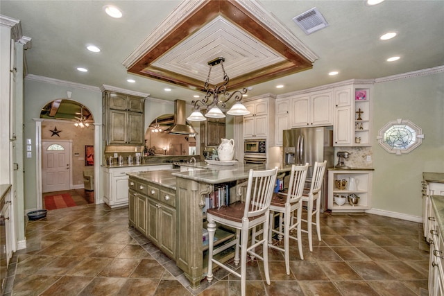 kitchen with a kitchen island, extractor fan, pendant lighting, appliances with stainless steel finishes, and a kitchen breakfast bar