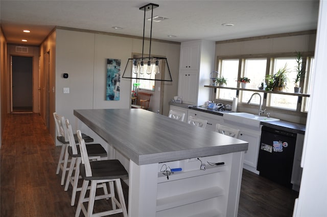 kitchen featuring pendant lighting, white cabinets, sink, and black dishwasher