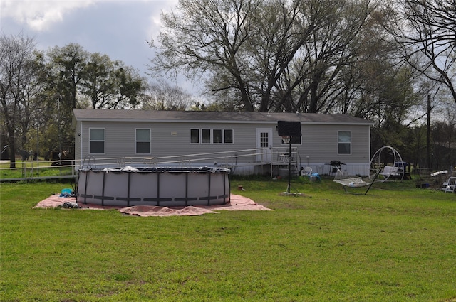 rear view of house featuring a lawn and a covered pool