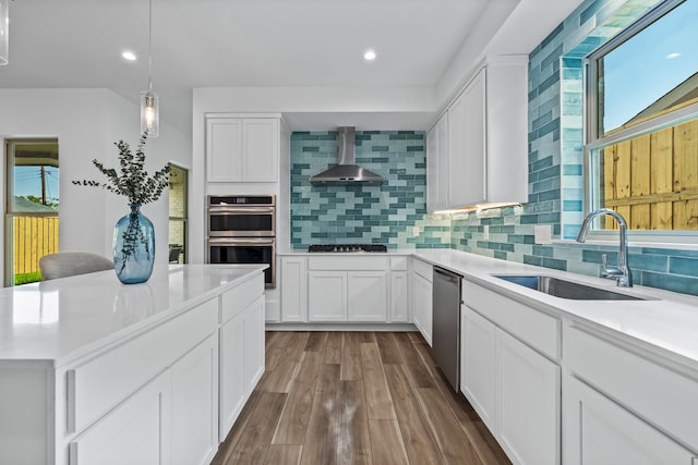 kitchen with wall chimney exhaust hood, dark hardwood / wood-style flooring, sink, stainless steel appliances, and white cabinets