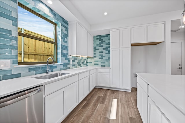 kitchen featuring light wood-type flooring, sink, white cabinetry, and stainless steel dishwasher