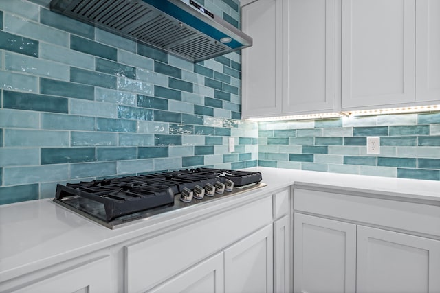 kitchen with wall chimney range hood, white cabinetry, and tasteful backsplash