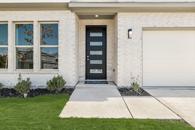 view of exterior entry featuring a garage and a yard