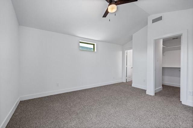 unfurnished bedroom featuring lofted ceiling, ceiling fan, a closet, a walk in closet, and carpet flooring