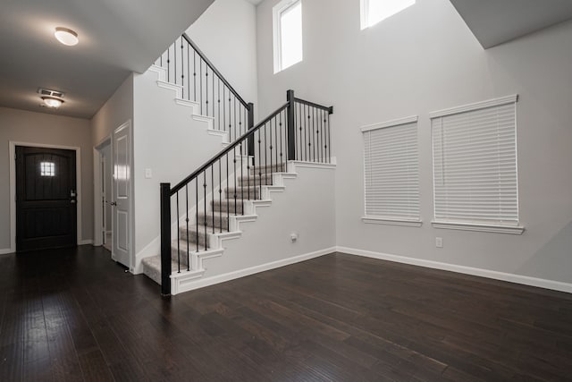 foyer entrance featuring dark hardwood / wood-style flooring and a towering ceiling