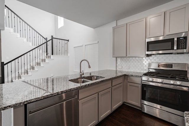 kitchen with gray cabinets, light stone counters, sink, and appliances with stainless steel finishes