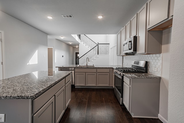 kitchen with stone counters, sink, dark hardwood / wood-style floors, decorative backsplash, and appliances with stainless steel finishes