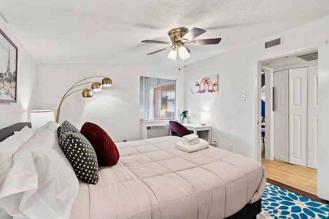 bedroom with hardwood / wood-style flooring, a textured ceiling, and ceiling fan