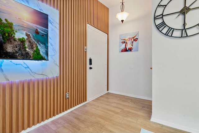 hall featuring light wood-type flooring and wood walls