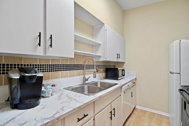 kitchen with stainless steel appliances, white cabinetry, sink, light wood-type flooring, and decorative backsplash