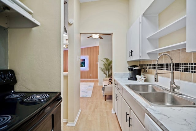 kitchen with sink, tasteful backsplash, black range with electric cooktop, white cabinetry, and light hardwood / wood-style flooring