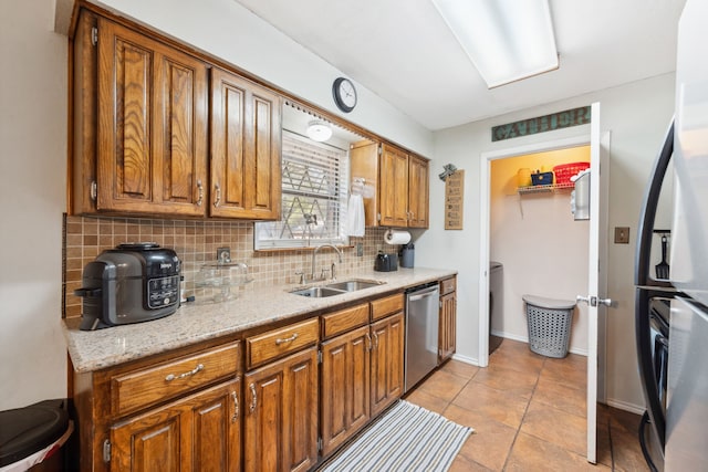 kitchen featuring light stone counters, light tile patterned floors, sink, tasteful backsplash, and stainless steel appliances