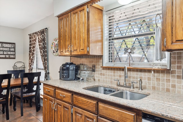 kitchen featuring light stone counters, light tile patterned floors, sink, backsplash, and dishwasher