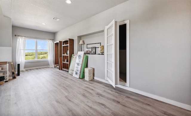 interior space with a textured ceiling and light hardwood / wood-style floors