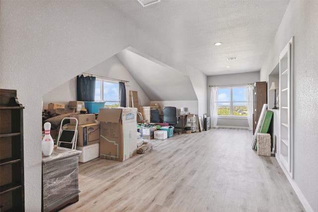 bonus room with a textured ceiling, lofted ceiling, and light hardwood / wood-style flooring