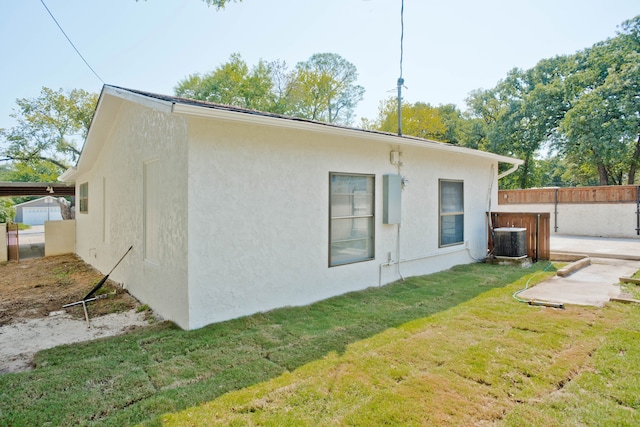 view of side of property with cooling unit, a lawn, and a patio area