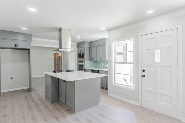 kitchen with appliances with stainless steel finishes, a kitchen island, gray cabinets, and exhaust hood