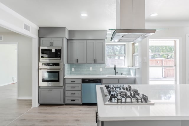 kitchen featuring island exhaust hood, a healthy amount of sunlight, sink, and stainless steel appliances