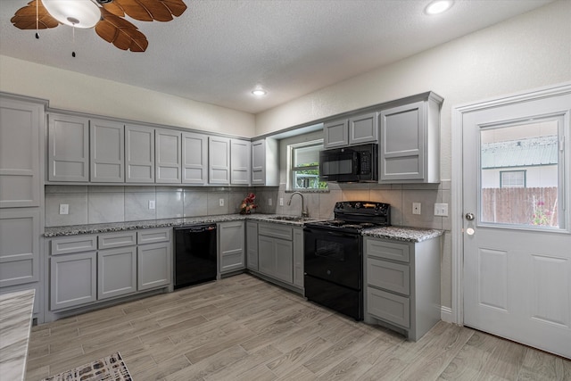 kitchen with a wealth of natural light, backsplash, sink, and black appliances