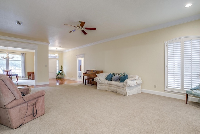 carpeted living room with ornamental molding and ceiling fan with notable chandelier