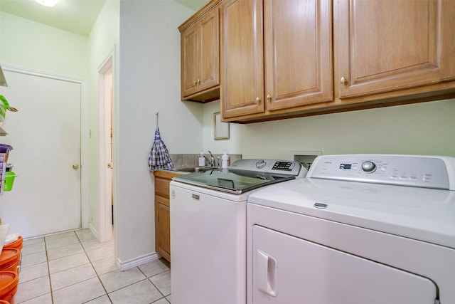 clothes washing area featuring cabinets, washer and dryer, light tile patterned flooring, and sink