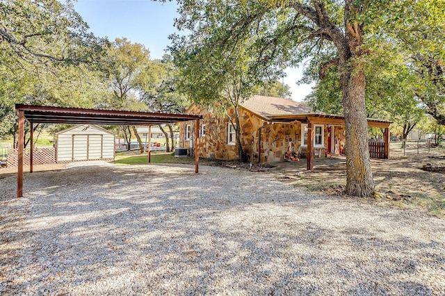 view of front of property with a carport, a storage unit, and central air condition unit