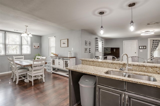 kitchen with sink, decorative light fixtures, dark wood-type flooring, and light stone countertops