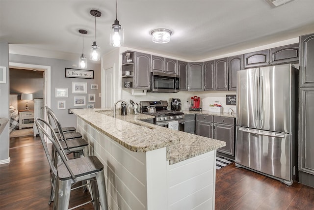 kitchen featuring appliances with stainless steel finishes, decorative light fixtures, a kitchen bar, light stone counters, and kitchen peninsula