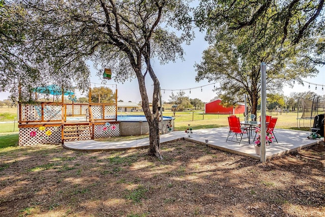 view of yard featuring a patio, a swimming pool side deck, and a trampoline