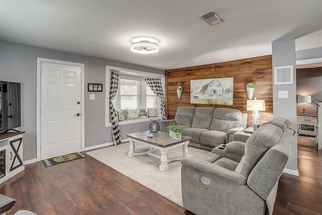 living room featuring dark wood-type flooring and wooden walls