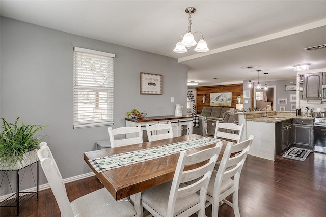 dining area with sink, dark hardwood / wood-style floors, and wood walls