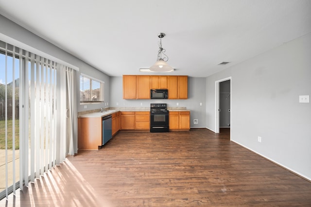 kitchen featuring dark wood-type flooring, black appliances, and pendant lighting