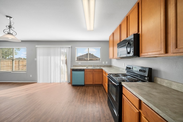 kitchen featuring dark hardwood / wood-style floors, black appliances, sink, and pendant lighting