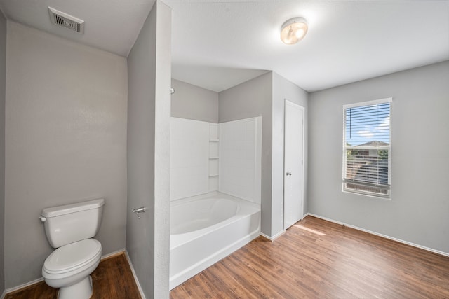 bathroom featuring bathtub / shower combination, hardwood / wood-style flooring, and toilet