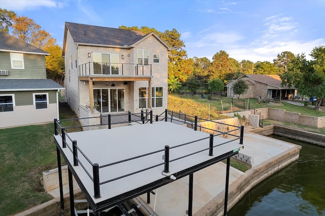 back of property featuring a balcony, a lawn, a water view, and central air condition unit